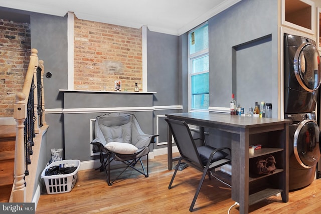 office space featuring stacked washer and clothes dryer, crown molding, hardwood / wood-style floors, and brick wall