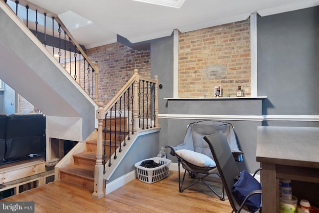 stairs featuring ornamental molding, hardwood / wood-style flooring, and brick wall