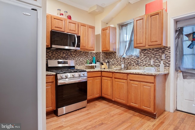 kitchen featuring sink, ornamental molding, light hardwood / wood-style flooring, backsplash, and stainless steel appliances