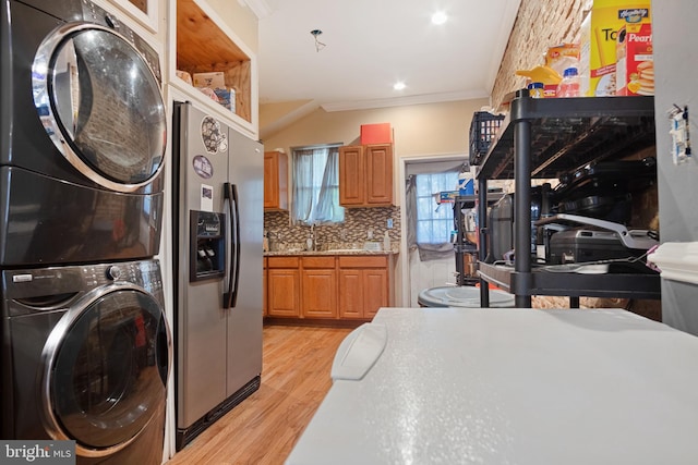 clothes washing area with ornamental molding, sink, stacked washing maching and dryer, and light hardwood / wood-style floors