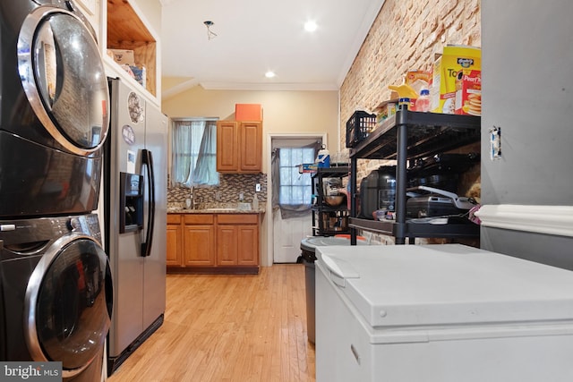 laundry area featuring ornamental molding, stacked washer / dryer, sink, and light hardwood / wood-style floors