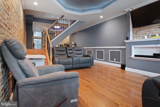 living room with crown molding, hardwood / wood-style floors, and a raised ceiling