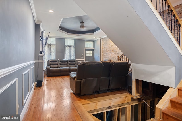 living room featuring ornamental molding, a tray ceiling, and light wood-type flooring