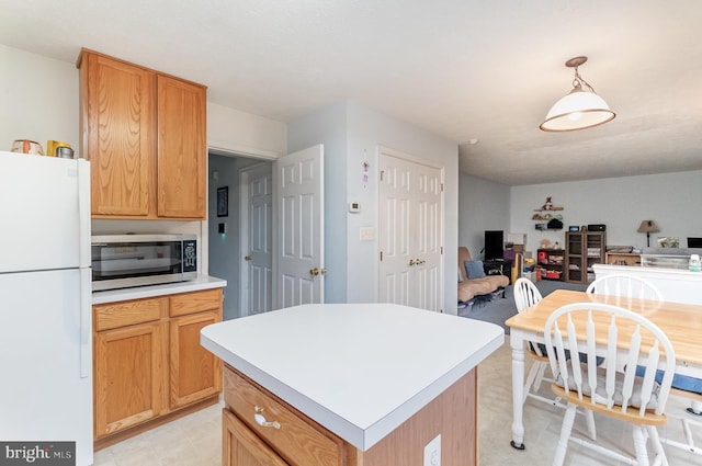 kitchen with decorative light fixtures, white fridge, and a center island