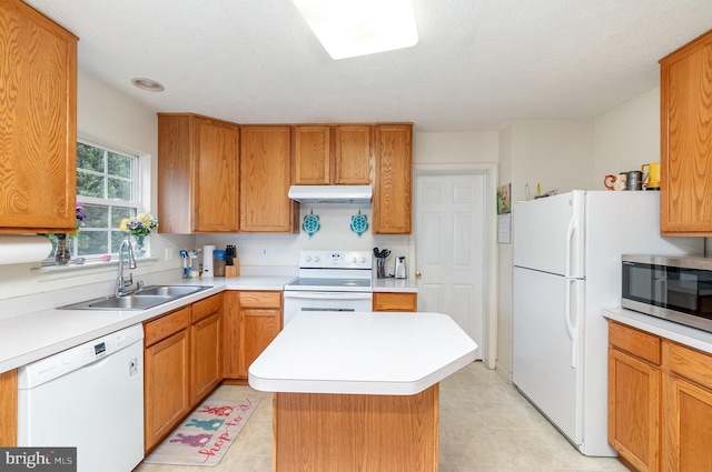 kitchen featuring white appliances, a textured ceiling, a kitchen island, and sink