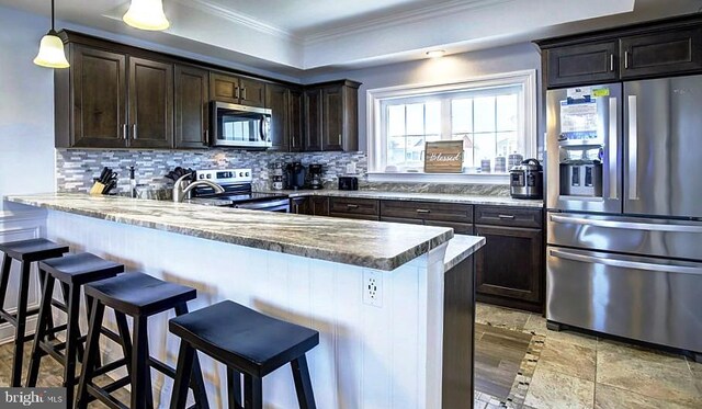 kitchen featuring decorative backsplash, a kitchen bar, stainless steel appliances, and light stone counters