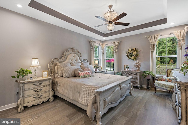 bedroom featuring ceiling fan, a raised ceiling, and dark wood-type flooring