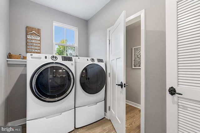 laundry area featuring separate washer and dryer and light hardwood / wood-style flooring