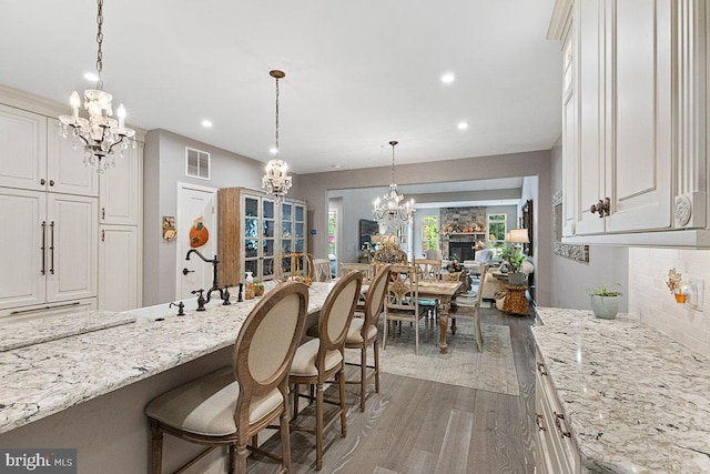 kitchen featuring backsplash, a breakfast bar area, an inviting chandelier, and dark wood-type flooring