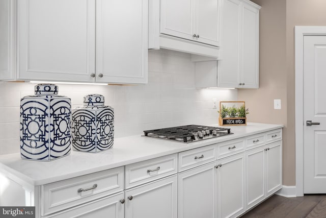 kitchen with stainless steel gas stovetop, white cabinetry, dark hardwood / wood-style floors, and backsplash