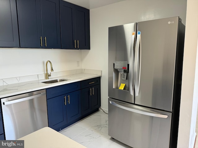 kitchen featuring blue cabinets, appliances with stainless steel finishes, light stone counters, and sink