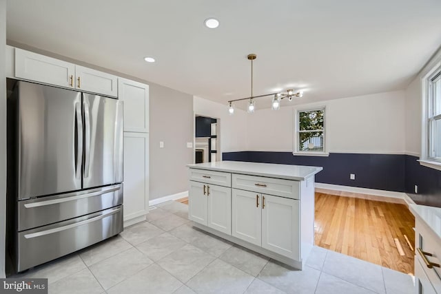 kitchen featuring light wood-type flooring, stainless steel refrigerator, white cabinetry, and decorative light fixtures