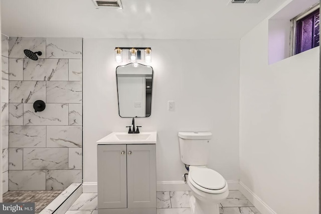 bathroom with vanity, toilet, and tiled shower