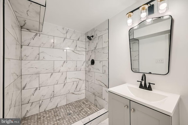 bathroom with a tile shower and vanity