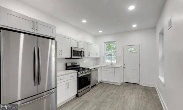 kitchen featuring sink, light hardwood / wood-style flooring, stainless steel appliances, and white cabinets