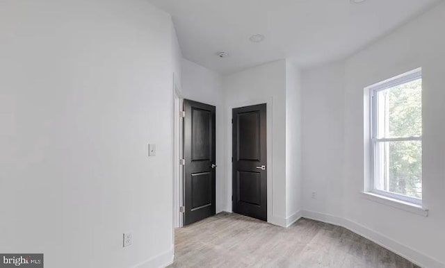 unfurnished bedroom with multiple windows and light wood-type flooring