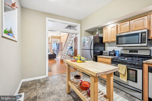 kitchen featuring light brown cabinets, stainless steel appliances, and tasteful backsplash