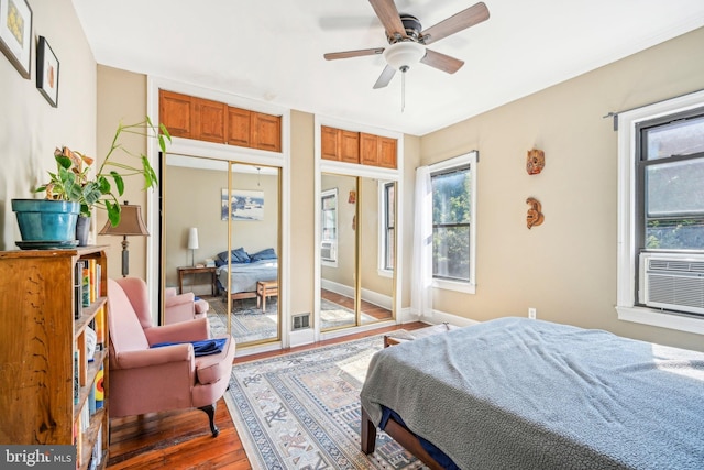 bedroom featuring wood-type flooring, ceiling fan, and multiple closets