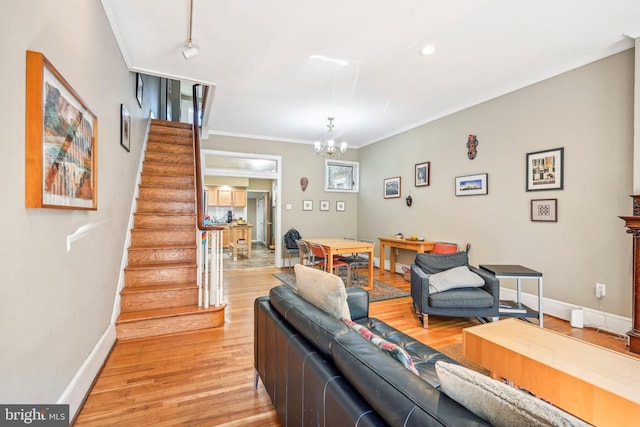 living room featuring ornamental molding, a chandelier, and light hardwood / wood-style floors