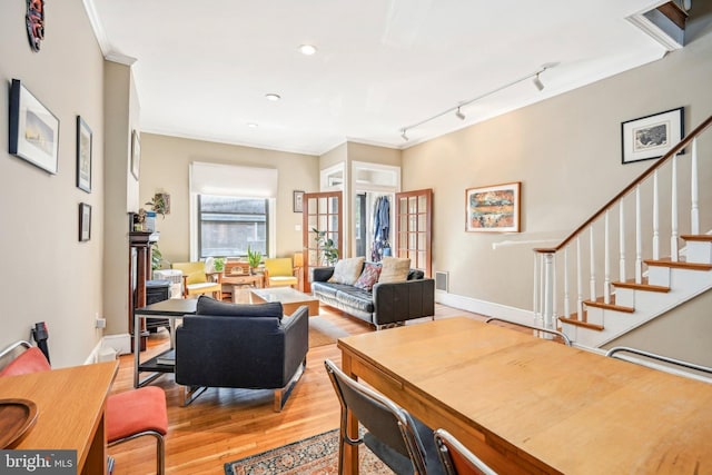 dining space featuring light wood-type flooring, crown molding, and track lighting