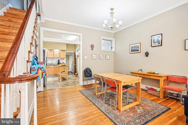 dining area featuring light wood-type flooring, ornamental molding, and a notable chandelier