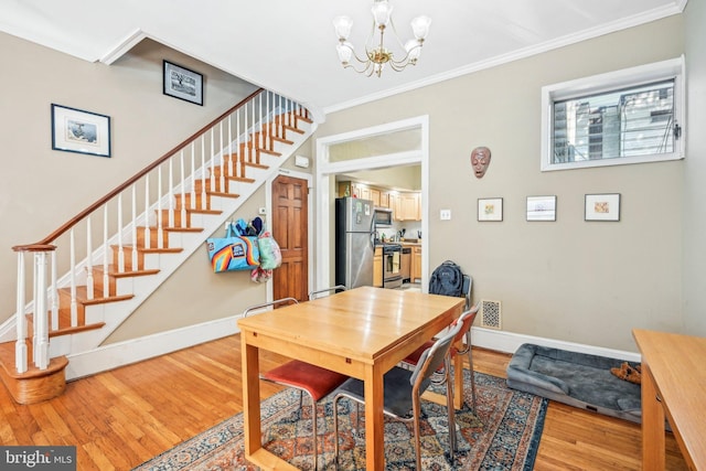 dining area featuring light wood-type flooring, a chandelier, and crown molding