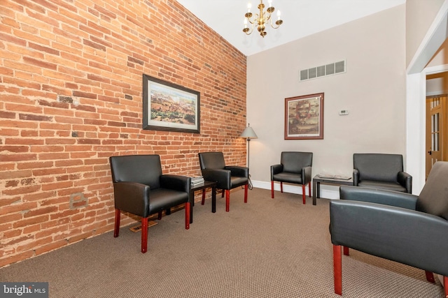 sitting room featuring carpet, a chandelier, and brick wall