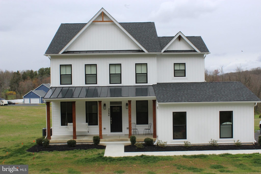 modern inspired farmhouse with a front lawn and covered porch