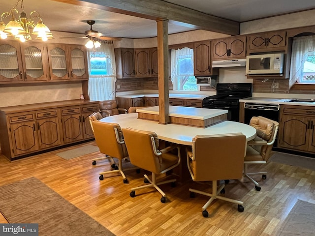 kitchen with black appliances, decorative light fixtures, light hardwood / wood-style floors, and a healthy amount of sunlight