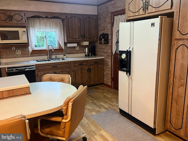 kitchen featuring tasteful backsplash, white appliances, light wood-type flooring, dark brown cabinets, and sink