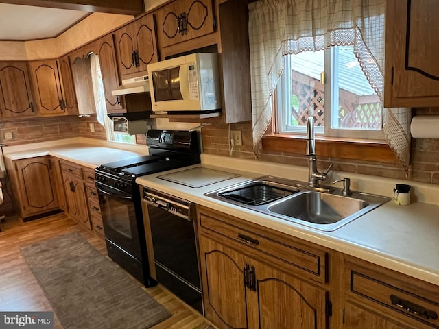 kitchen featuring light wood-type flooring, sink, tasteful backsplash, and black appliances