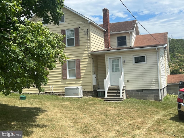 rear view of property featuring central AC unit and a lawn