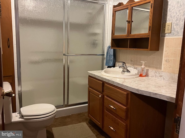 bathroom with vanity, a shower with shower door, toilet, and decorative backsplash