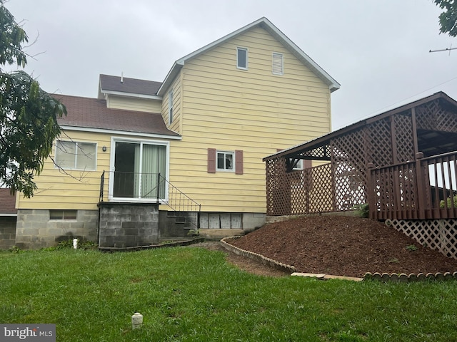 rear view of house featuring a wooden deck and a yard