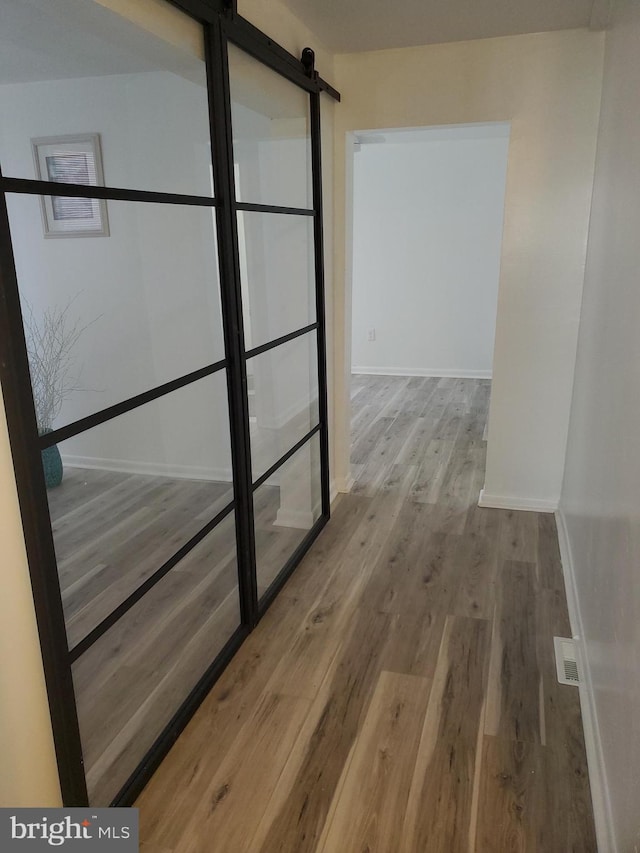 hall with hardwood / wood-style floors and a barn door