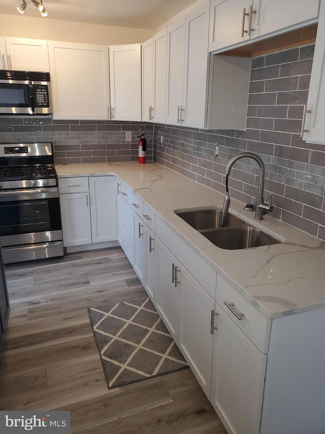 kitchen featuring white cabinets, appliances with stainless steel finishes, sink, and light hardwood / wood-style flooring