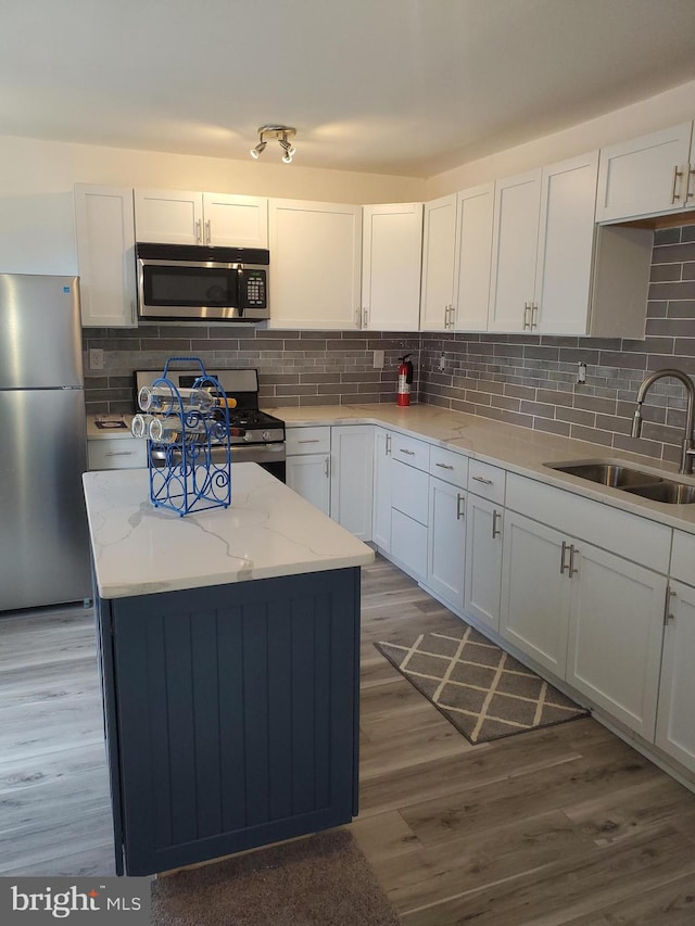 kitchen with sink, appliances with stainless steel finishes, dark hardwood / wood-style flooring, and white cabinetry