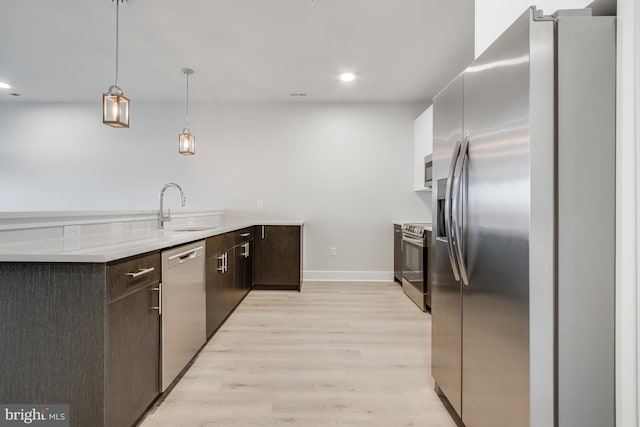 kitchen featuring light wood-type flooring, sink, hanging light fixtures, stainless steel appliances, and dark brown cabinetry