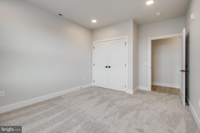 unfurnished bedroom featuring light colored carpet and a closet