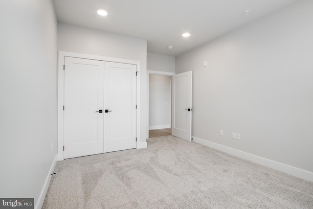 unfurnished bedroom featuring light colored carpet and a closet