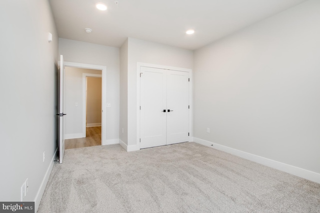 unfurnished bedroom featuring light colored carpet and a closet