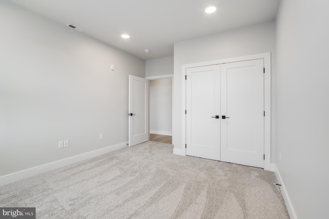 unfurnished bedroom with a closet and light colored carpet