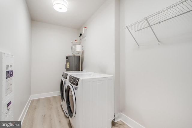 washroom with electric water heater, light wood-type flooring, and washing machine and dryer