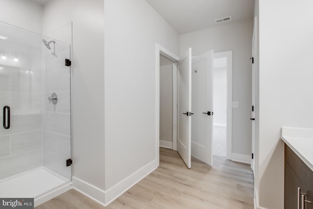 bathroom featuring wood-type flooring, a shower with shower door, and vanity