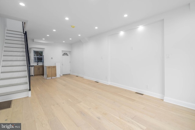 unfurnished living room featuring sink and light hardwood / wood-style floors