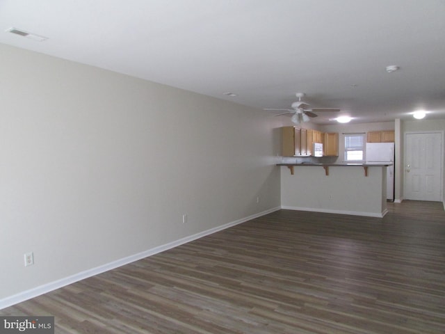 unfurnished living room featuring dark wood-type flooring and ceiling fan