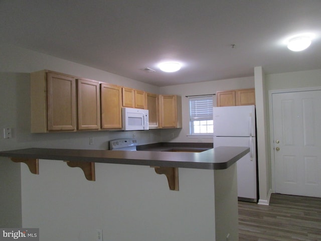 kitchen with white appliances, light brown cabinets, a breakfast bar area, dark wood-type flooring, and kitchen peninsula