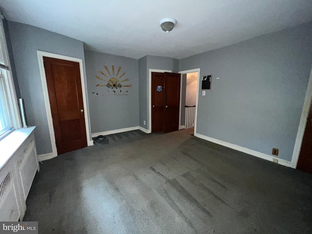 interior space featuring dark carpet and radiator heating unit