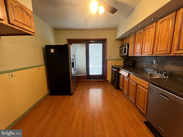 kitchen featuring tile walls, stainless steel appliances, light wood-type flooring, and sink