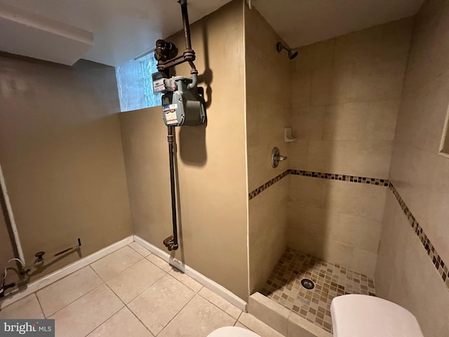 bathroom with tiled shower, toilet, and tile patterned flooring